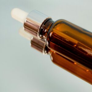 Close-up of a brown dropper bottle reflecting on a glass surface, perfect for skincare or aromatherapy themes.