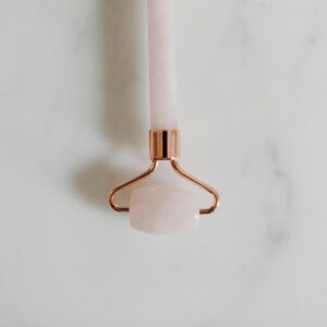 A close-up of a rose quartz facial roller on a marble surface, symbolizing luxury skincare.