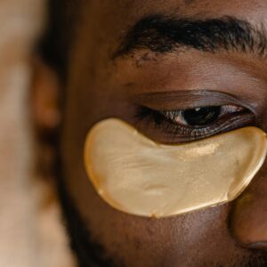 Close-up of a man's eye with a gold under eye patch, focusing on skincare and rejuvenation.